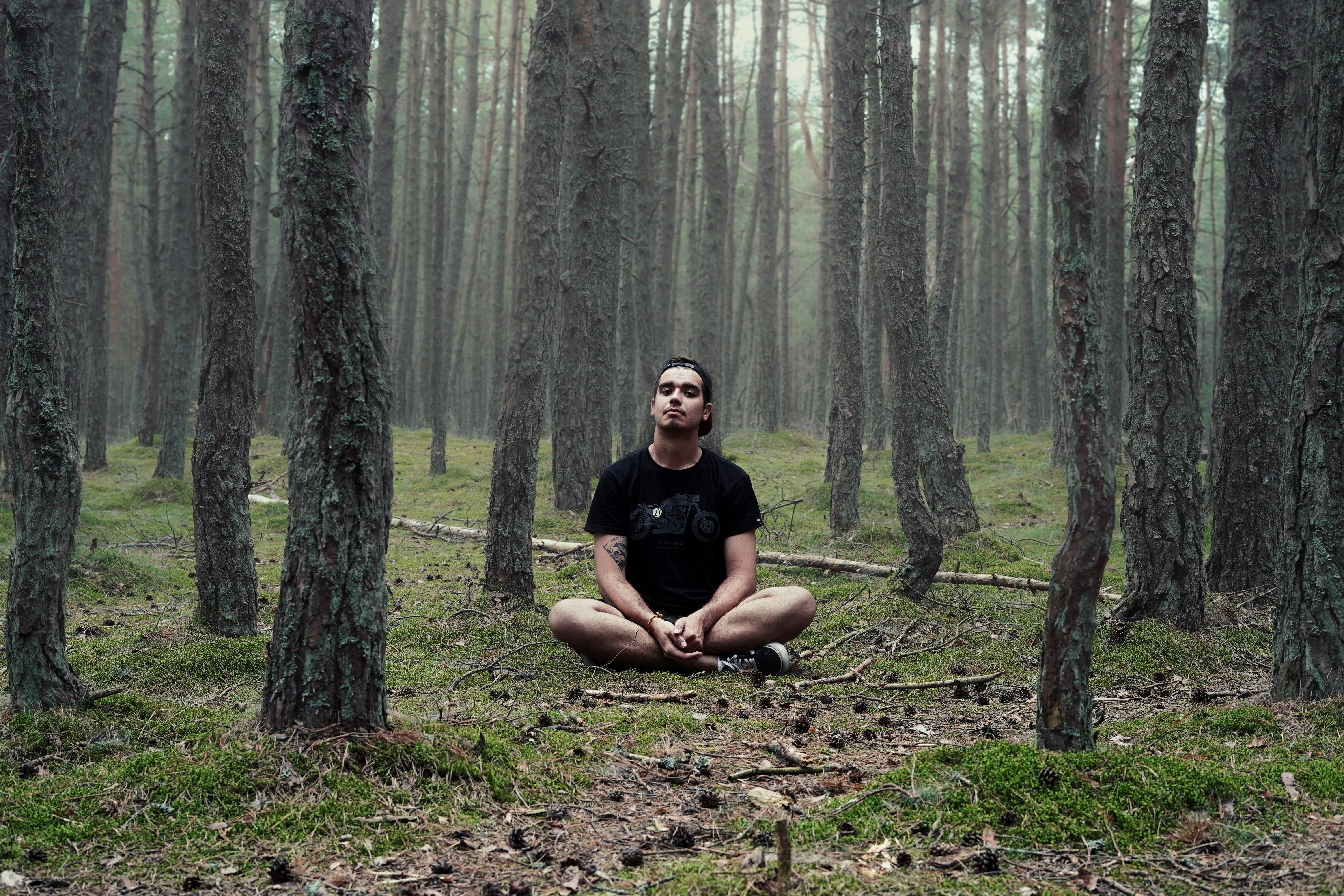 man in black shirt sitting in woods